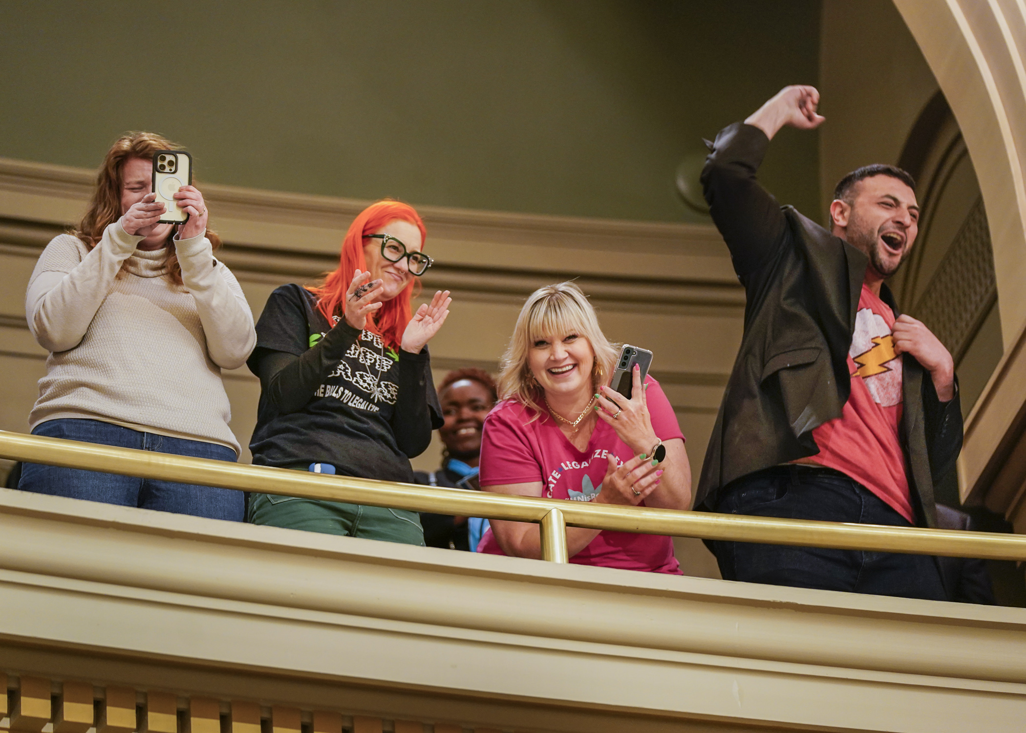 Cheering from the gallery, supporters of cannabis legalization Rachel Kane, Jamie Coyle, Bridget Pinder and Emilio Medina celebrate the passage of HF100 off the House Floor April 25. (Photo by Catherine Davis)